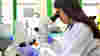 A medical researcher in the lab, looking into a telescope