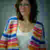 Josie has dark shoulder lenth hair. She has a big smile and wears a stripey jumper reflecting her sunny disposition.
