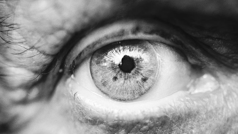 Extreme close up of an eye in black and white. The lines around the eye imply it belongs to someone of an older age. 