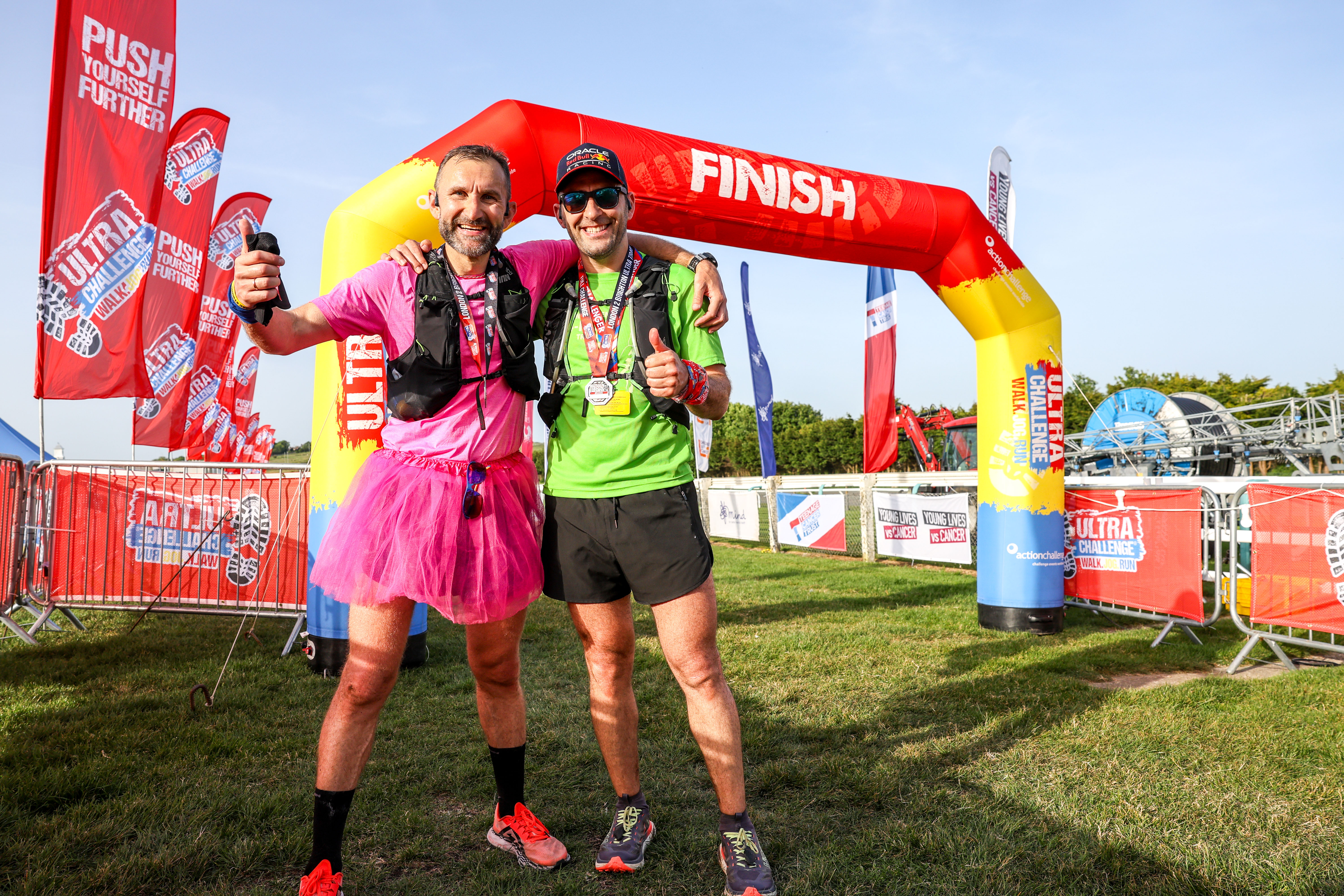 Two people proudly displaying their medal after completing the London 2 Brighton Ultra Challenge.