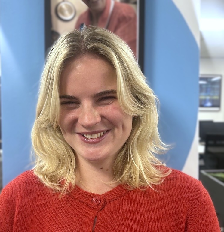 Ella from the Fight for Sight Impact Team - she is smiley and has blond hair, she is standing in the Fight for Sight head office