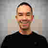 Chris Yiu Director of Public Policy at Meta. Chris has short cropped hair. He is wearing a t-shirt with the meta logo.