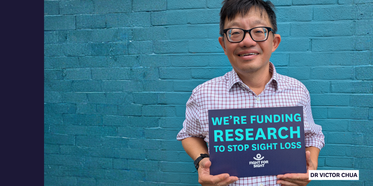 Dr Chua holding up a Fight for Sight sign that reads We're funding research to stop sight loss.