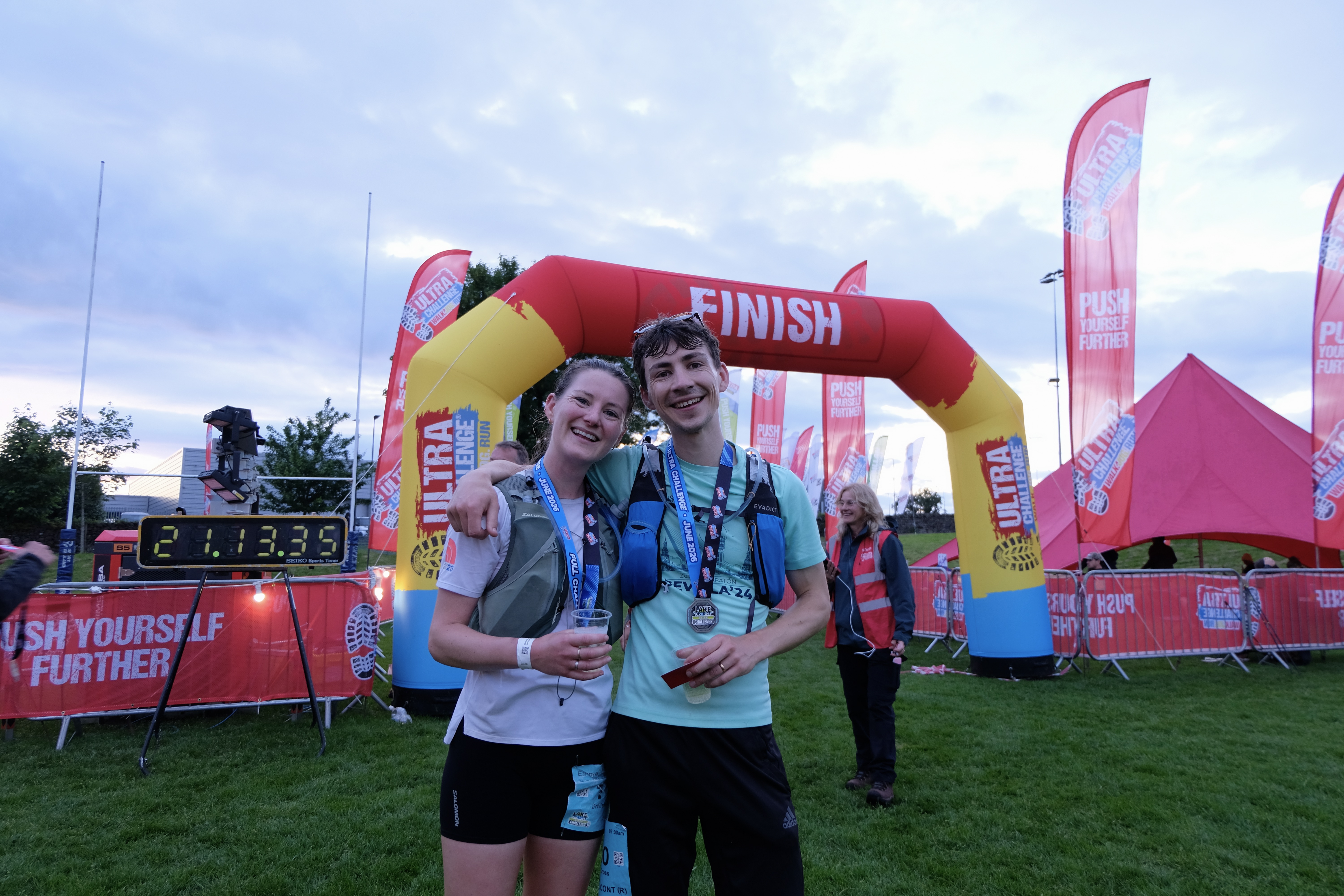 Two people proudly wearing their medal after completing the Lake District Challenge