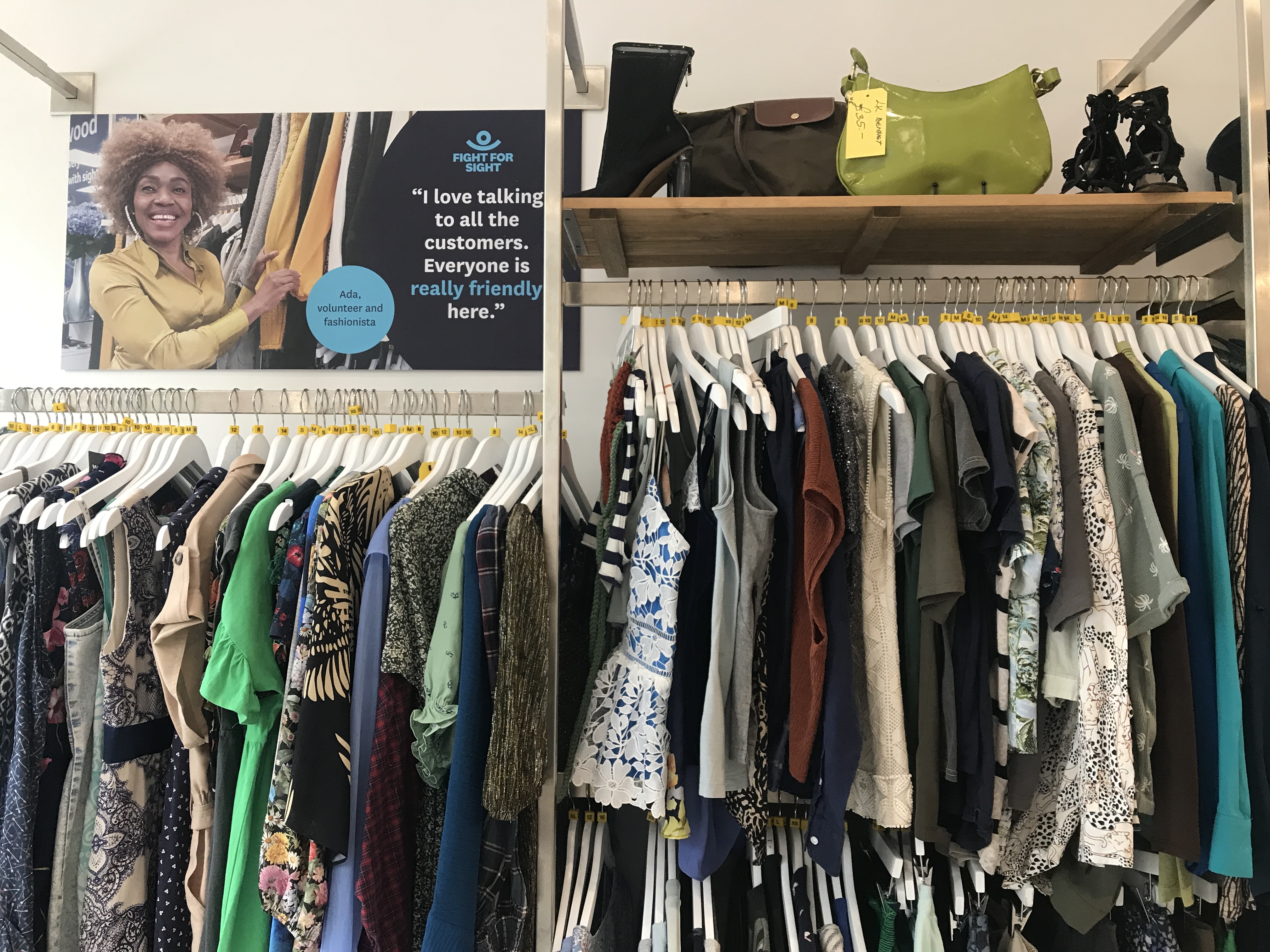 An assortment of womenswear in our Kensal Rise shop. Above the rails is a poster of one of our volunteers.