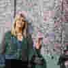 Paula Long, a stylish blonde lady who has been diagnosed with Glaucoma, in front of a mural she painted.