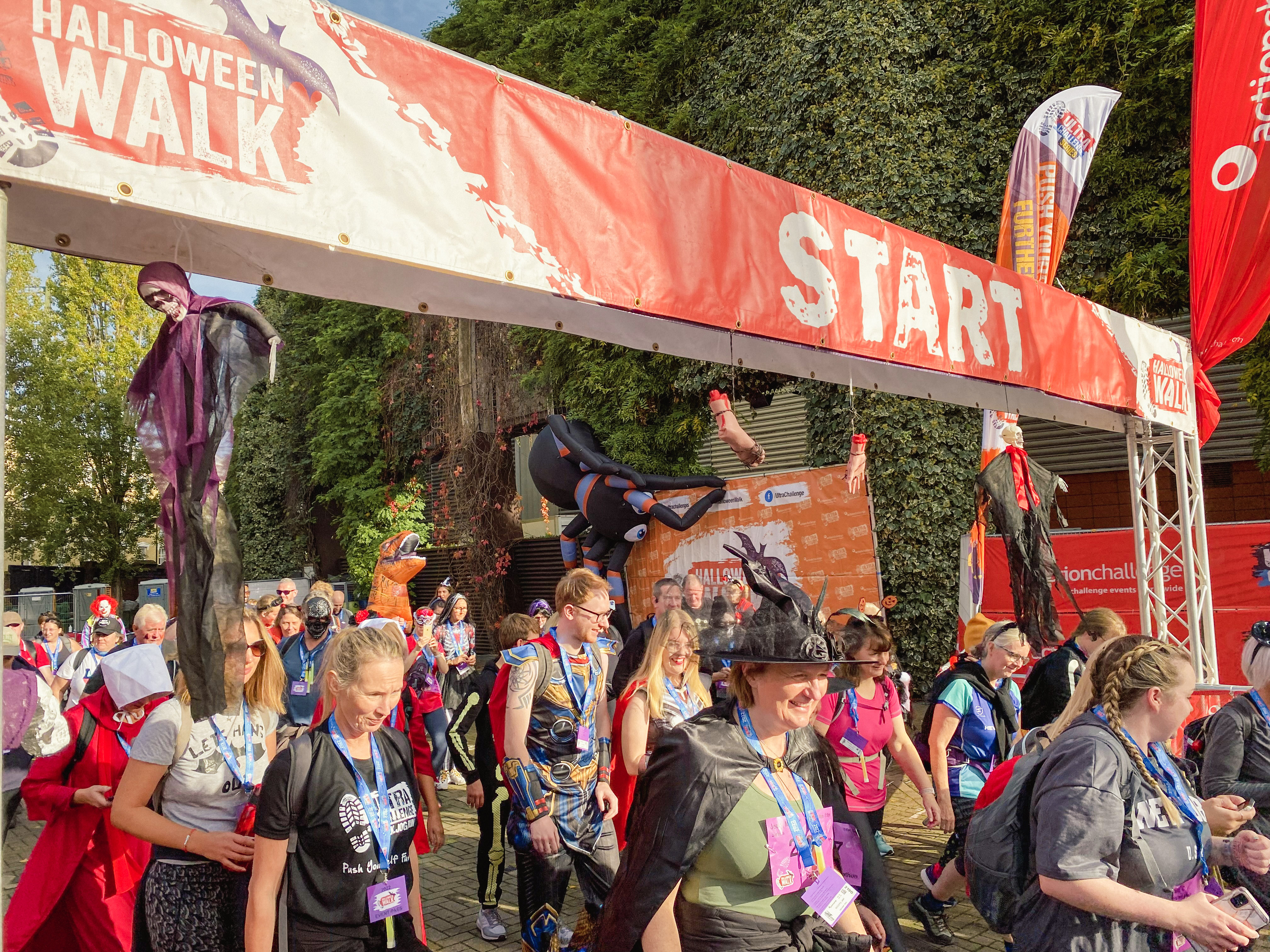 People crossing the start line of the Halloween Walk wearing Halloween themed outfits