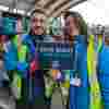 TfL Lost Property donation to Fight for Sight man and lady holding up a sign at the Lost Property Depot that says Save Sight. Change Lives.