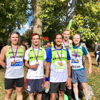 John and colleagues standing under a tree wearing Fight for Sight running vests and newly acquired medals, after running London Landmarks Half Marathon