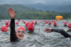 Swimmers in open water, one swimmer turned back to camera smiling and waving