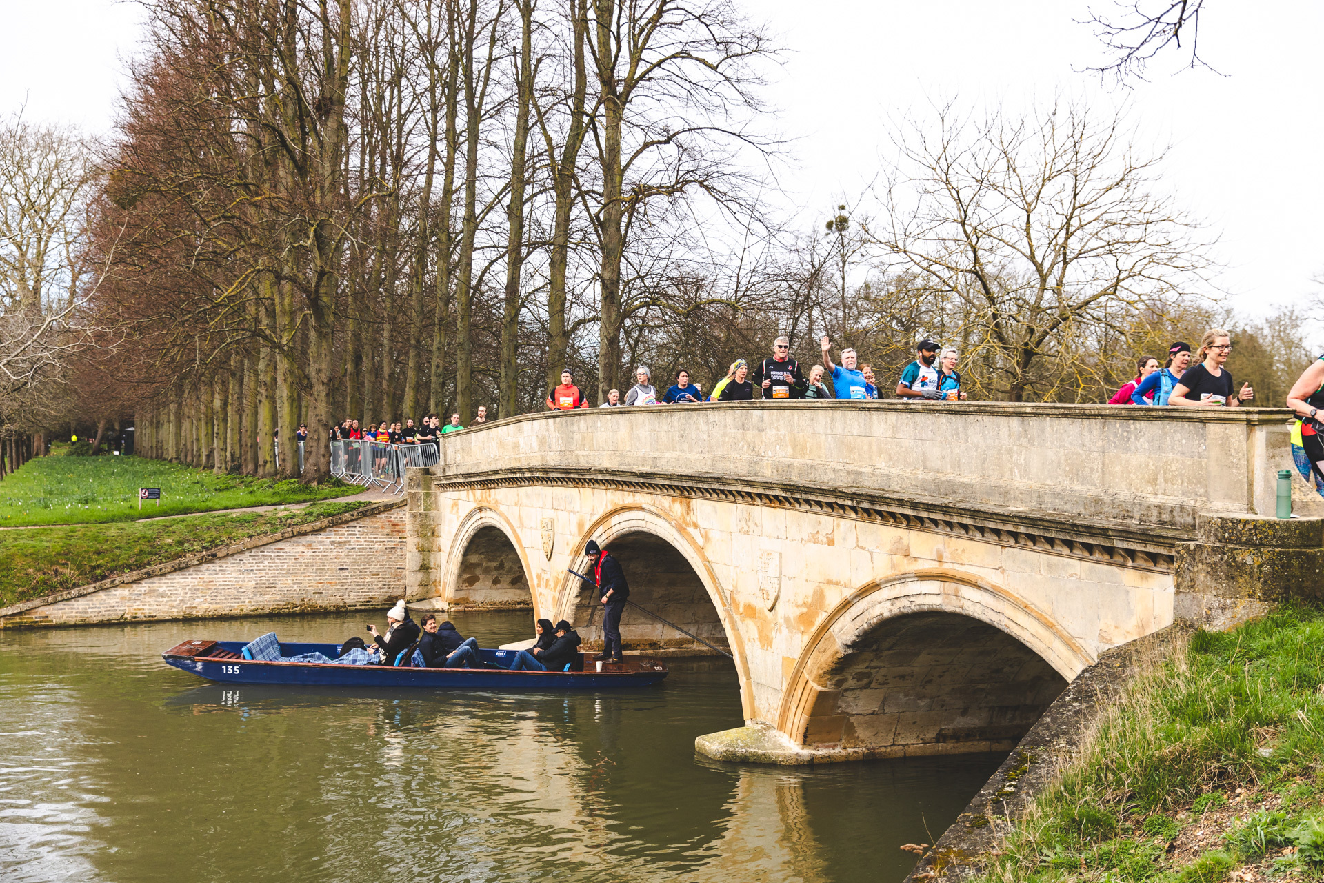 Runners waving whilst crossing a bridge on the route of the Cambridge Half Marathon