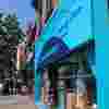Ealing Broadway Fight for Sight Charity Shop a turquoise shop with a navy Logo and the words Save Sight. Change Lives. The window features mannequins that are wearing fashion donated by Ealing locals.