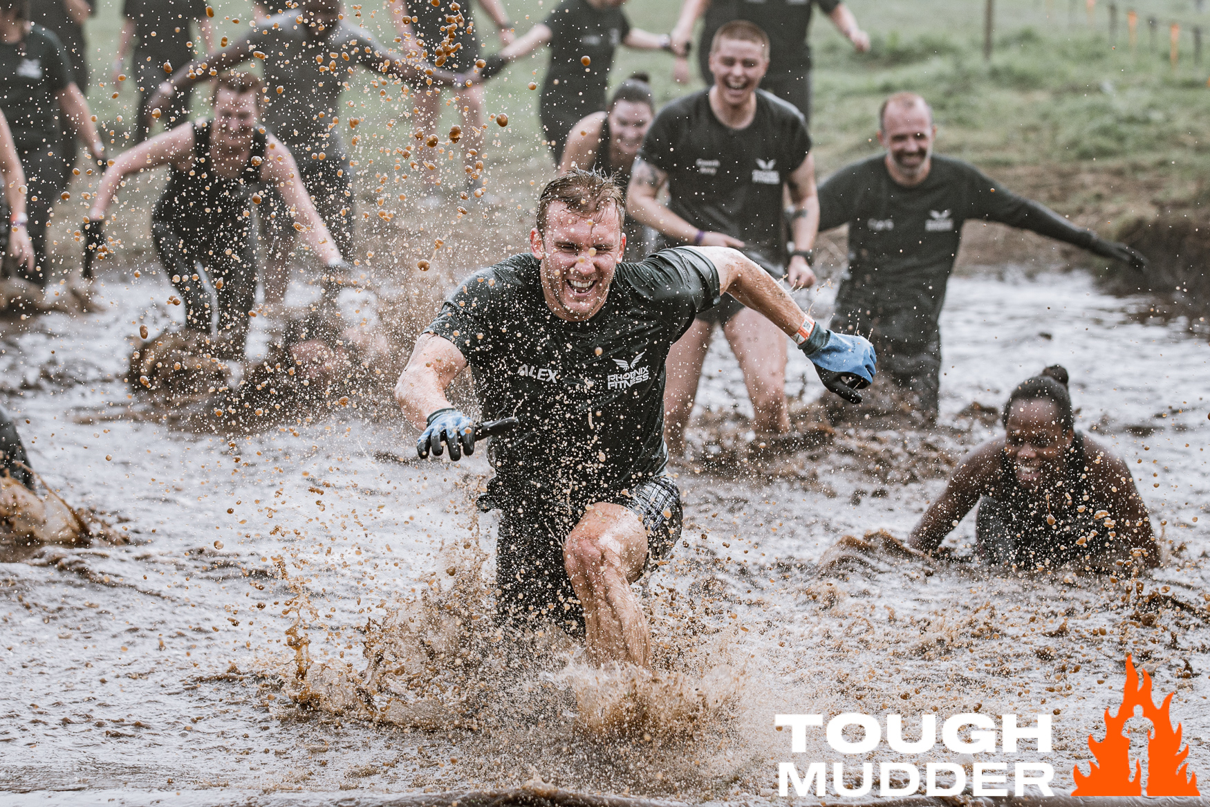 People running through muddy water while taking part in the Tough Mudder