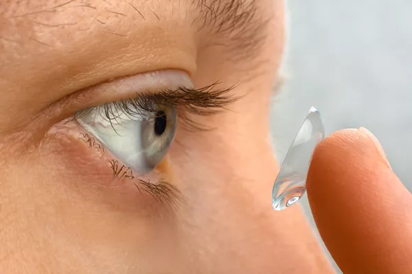A close up of a person putting a contact lens in.