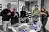 Fight for Sight staff stand around a table looking very cheerfully at a selection of cupcakes with our logo on them