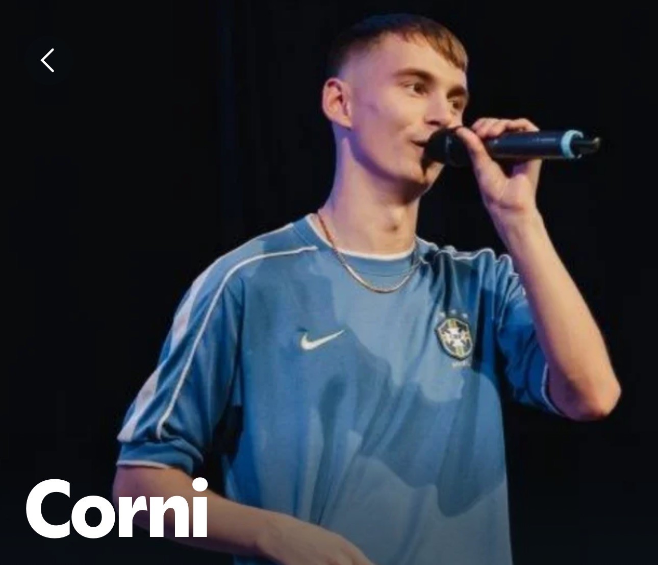 Cornelius McGrath who lives with Leber Hereditary Optic Nueropathy holding a microphone. He wears a pale blue top