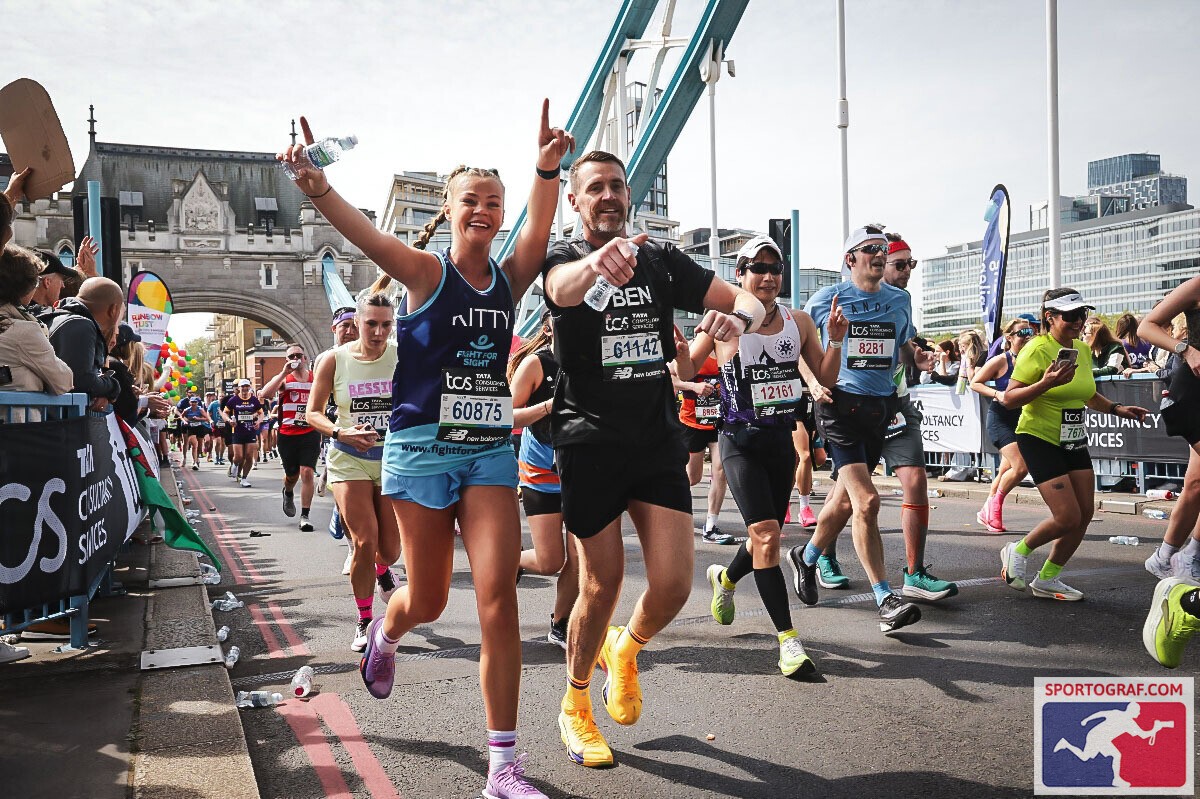 A Fight for Sight supporter smiling and waving while running over Tower Bridge in the London Marathon