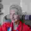 Elizabeth Maxwell in profile - she sits in a chair wearing a red blouse with a blue scarf