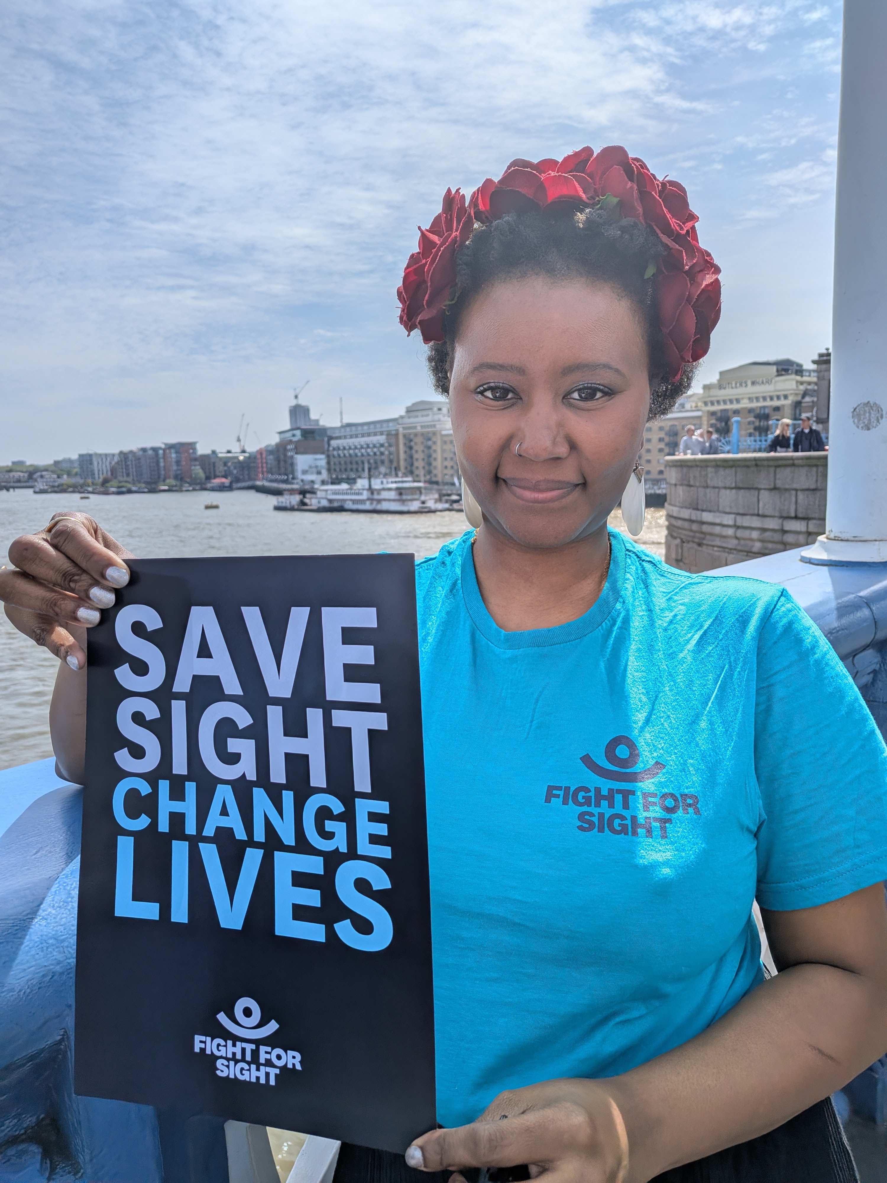 Shakirat from Fight for Sight holding a Fight for Sight sign that says Save Sight Change Lives