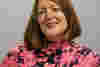 Emma has shoulder lenght red hair and wears a bright top. She is smiling for the camera. 