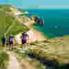 People walking the Jurassic Coast Challenge with Durdle Door and the coastline in the background