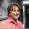 Adi is standing in front of a mirror. He is laughing.