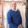 A photo of Phil Beavan from the waist up standing in front of a shop display.