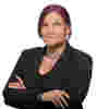 Leonie Watson who has pink hair and wears a suit with her arms folded