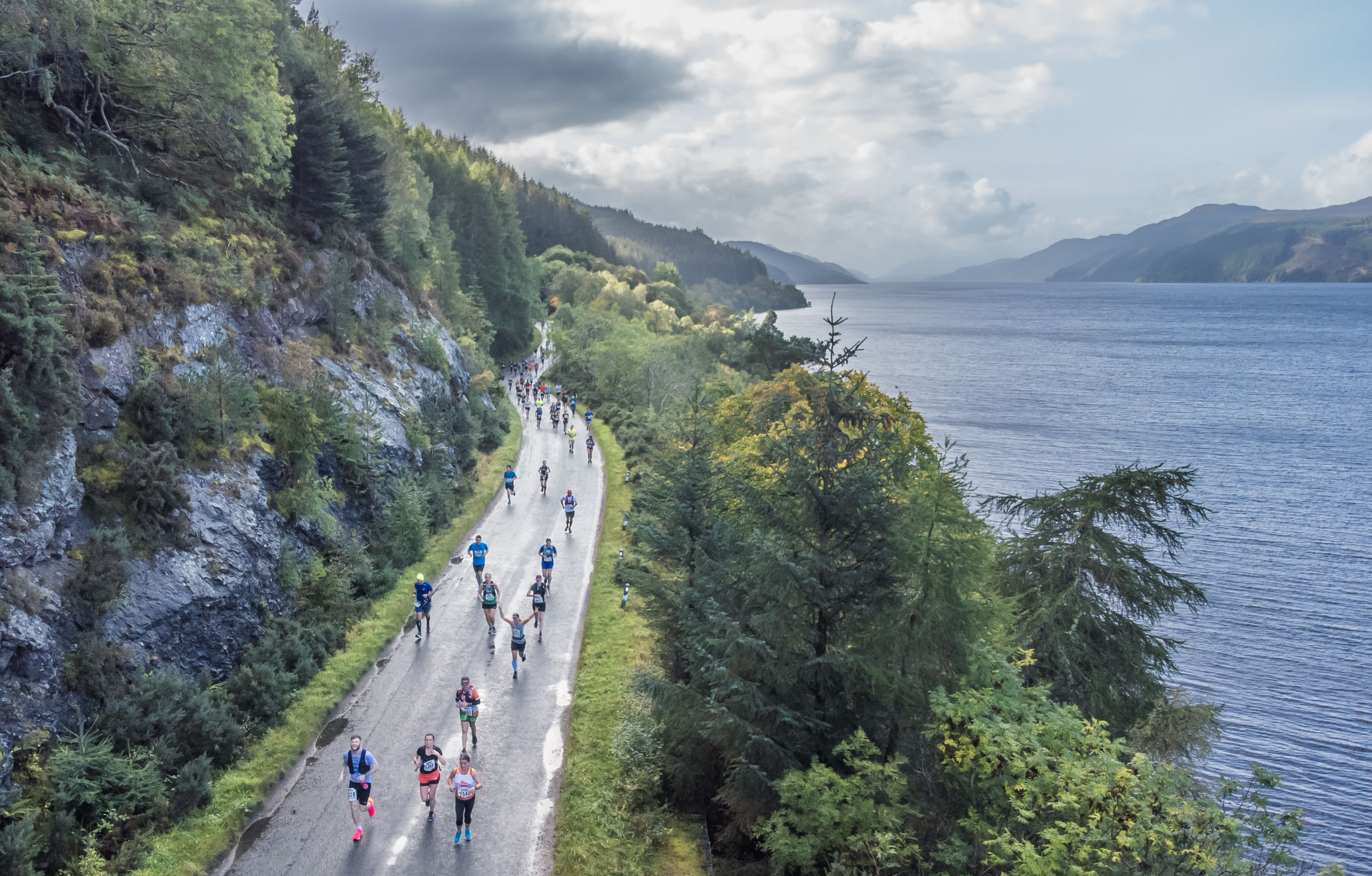Overhead views of people running in the Loch Ness Marathon, with a backdrop of the loch