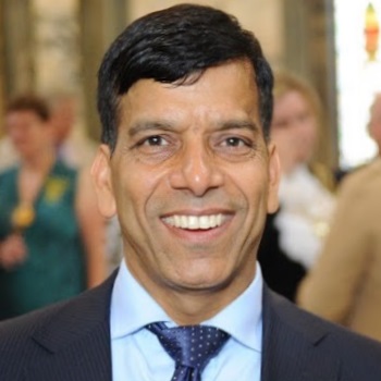 A headshot of Alderman Prem wearing a dark blue suit, smiling broadly at the camera