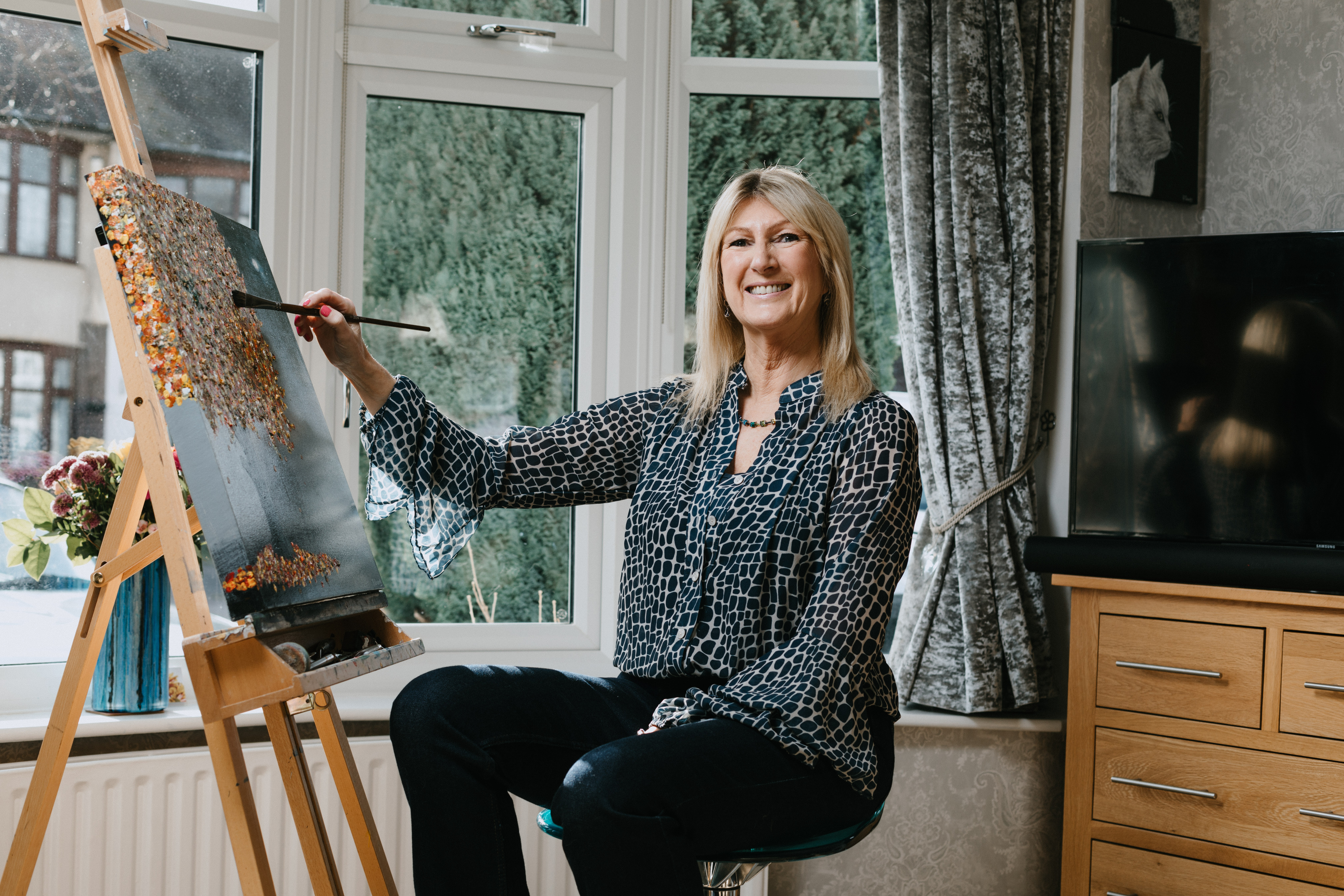 Paula Long, a stylish blonde lady who has been diagnosed with Glaucoma working on a painting sat at her easel.