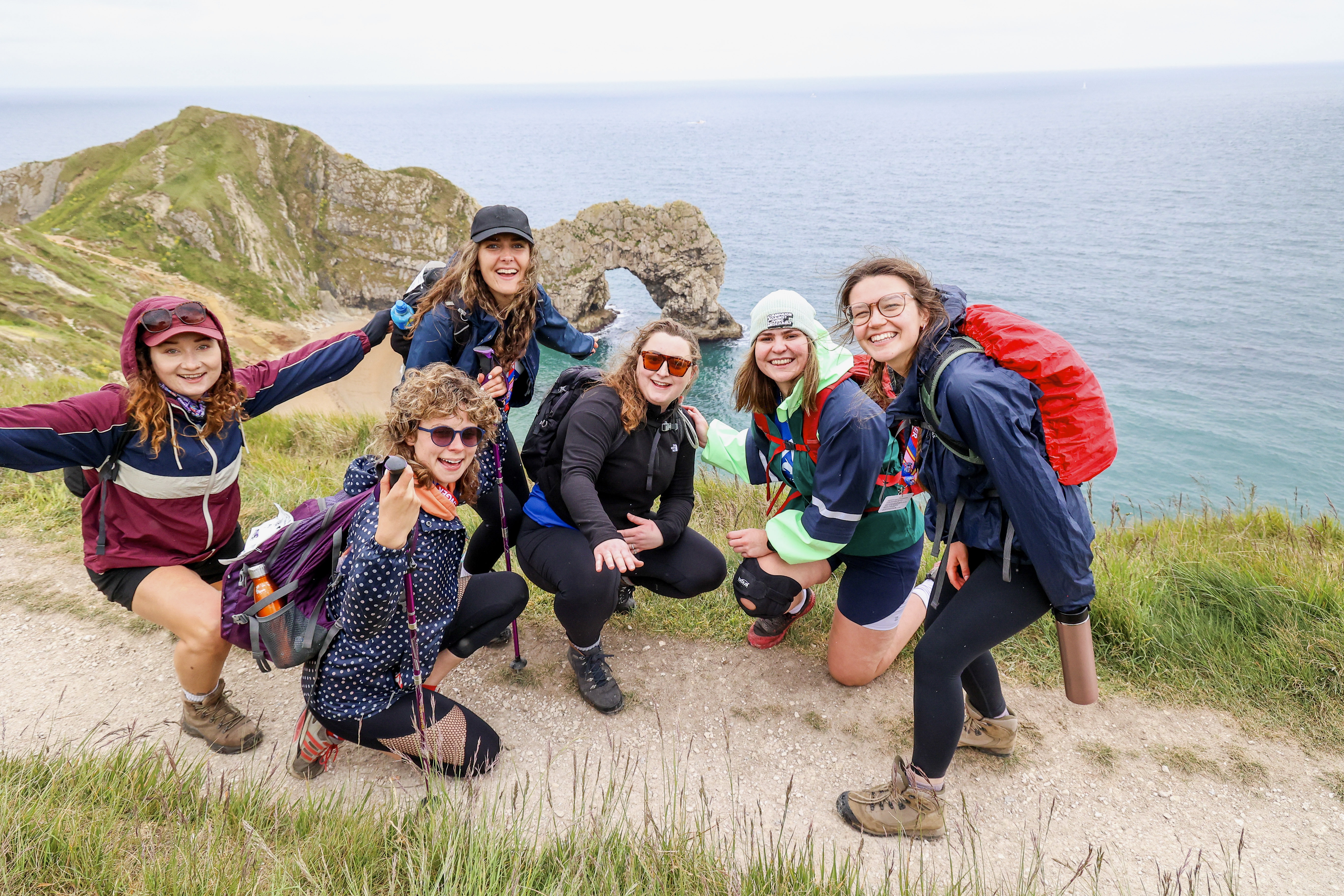 A group of walkers taking part in the Jurassic Coast Ultra Challenge, with Durdle Door behind them