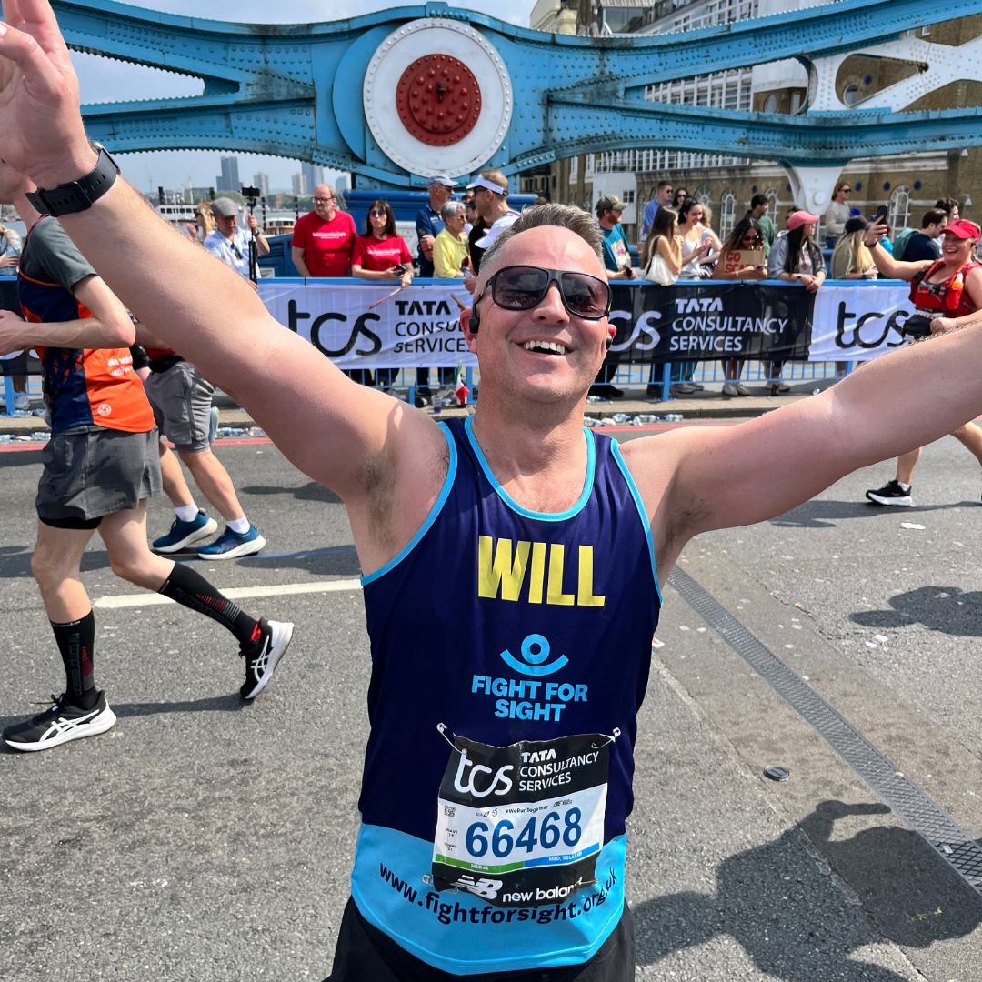 Fight for Sight supporter Will is stretching out his arms to wave to the cheerpoint on Tower Bridge, whilst taking part in the London Marathon