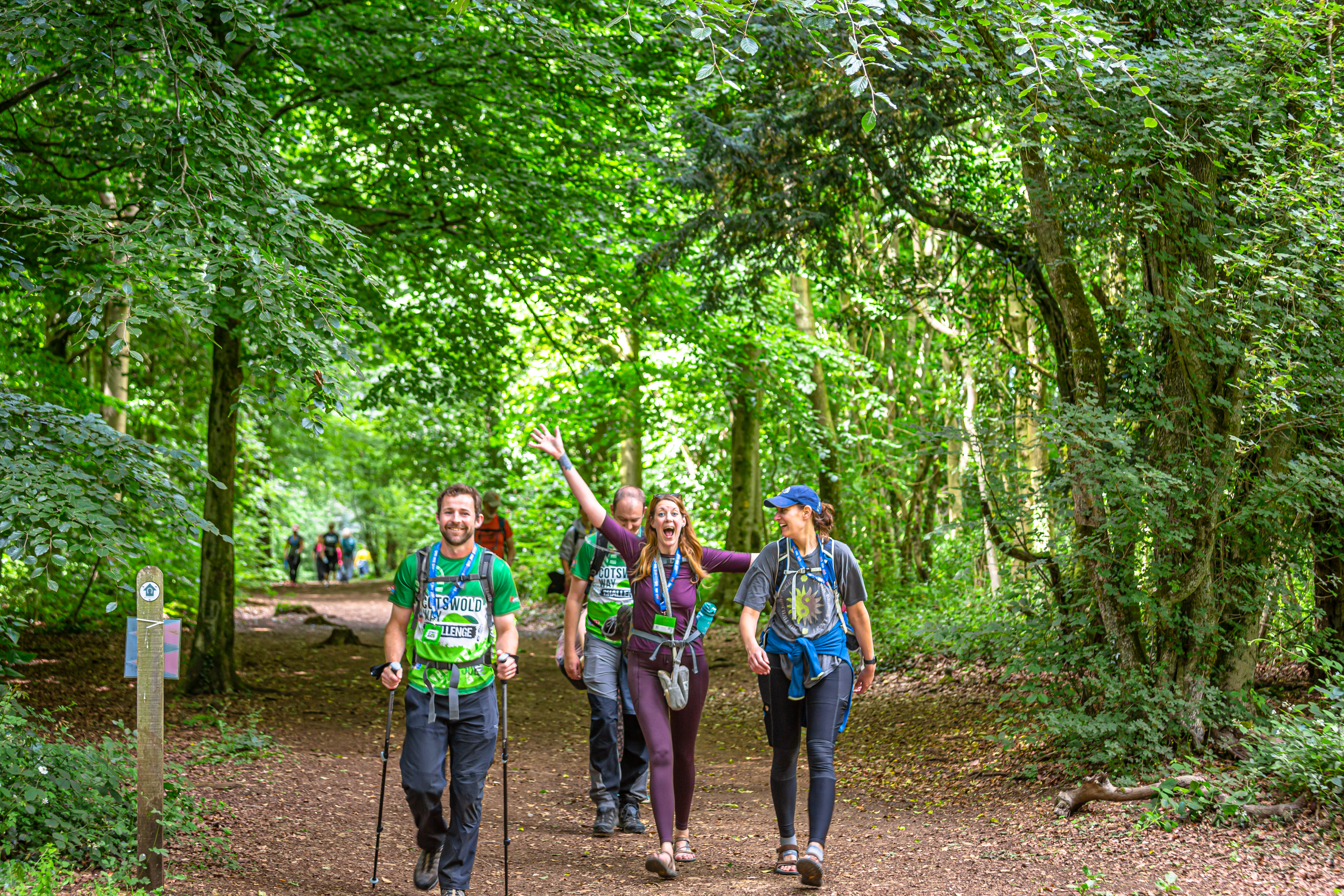 Walkers smiling and waving whilst taking part in the Cotswold Way Challenge