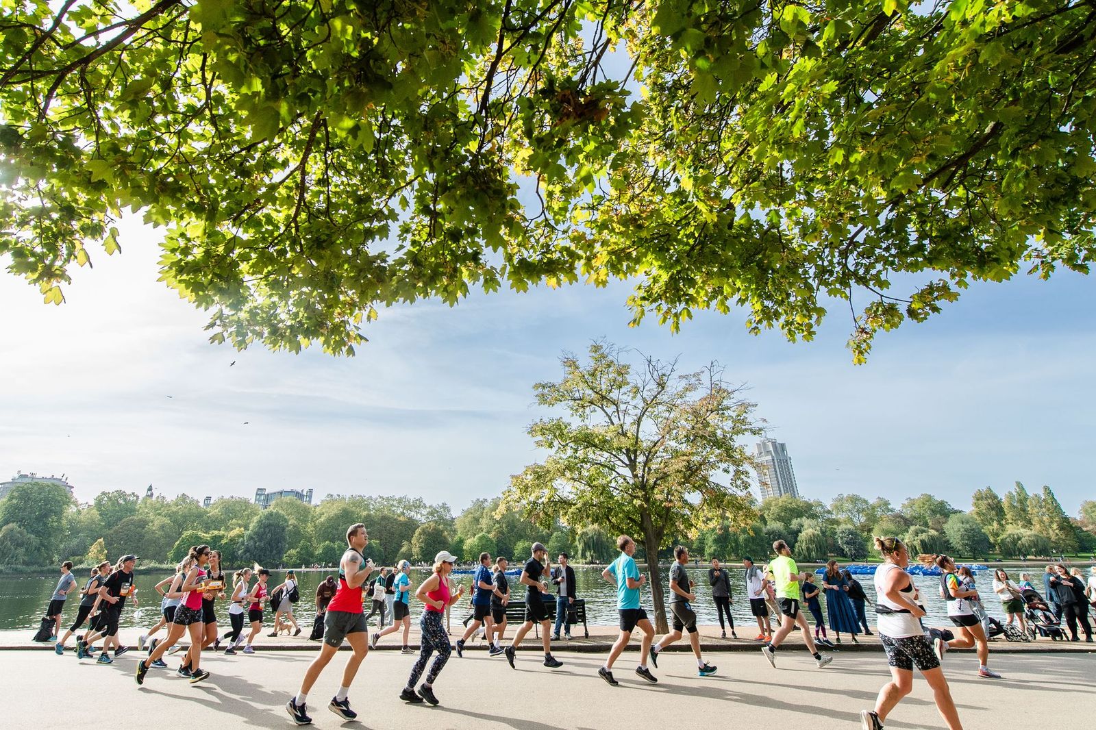 Runners in the sunshine, running along a path beside a lake at the Royal Parks Half Marathon